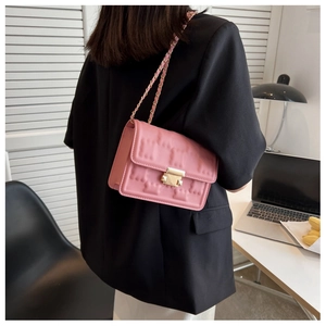 Detailed view of pink square embossed flap bag with gold chain strap on a model