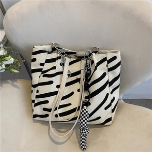 Striped canvas tote bag with zebra print and checkered charm on a cream seat