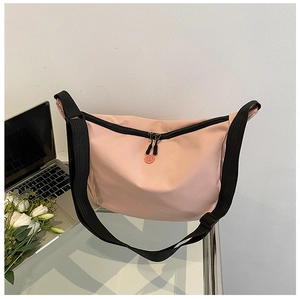 Detailed macro of pink oxford fabric crossbody bag featuring adjustable black strap and logo
