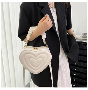 Detail of a chic heart-shaped quilted handbag in cream white with ruffled cloud handle
