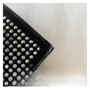 Detailed macro view of black suede texture with silver rhinestone studs on a square bag
