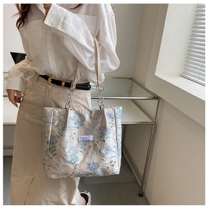 Close-up of vintage floral tote bag with chain strap and leather stitching details