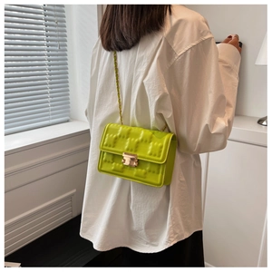 Detail of neon green quilted crossbody bag with gold chain strap and square texture