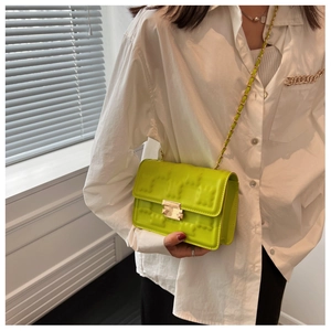 Detail of neon green crossbody bag with embossed texture and gold chain strap