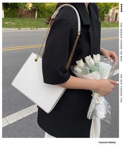 Détail du sac blanc à motif crocodile avec chaîne dorée et bouquet de tulipes