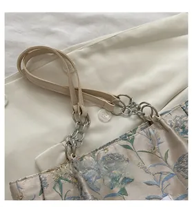 Detail of floral jacquard tote bag with elegant silver chain and leather shoulder strap