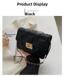 Detail of black quilted leather crossbody bag featuring gold hardware and chain strap