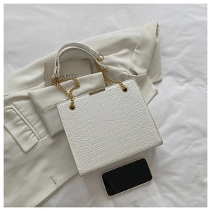 Détail du sac blanc à motif crocodile avec chaîne dorée et accessoires brillants