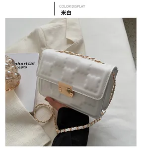 Detail of off-white crossbody bag featuring quilted texture and gold chain strap