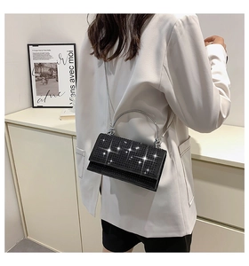 Detail of elegant black rhinestone crossbody bag with silver ring handle on a model