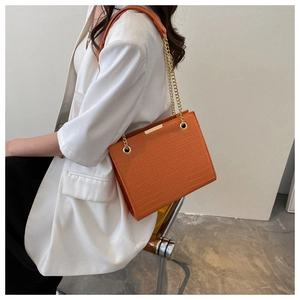 Détail du sac bandoulière orange à motif crocodile avec chaîne et garniture dorée