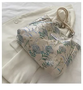 Close-up of floral jacquard tote bag featuring leather handles and silver chain detail