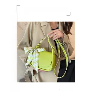 Detail of light green crossbody bag with checkered silk scarf tied on the strap