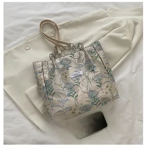 Detailed close-up of vintage tote bag with blue floral embroidery and metal chain strap