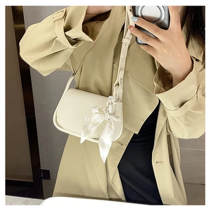 Close-up of beige leather mini flap bag featuring decorative silk scarf and adjustable strap