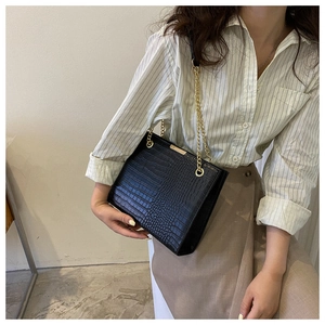 Détail du sac en cuir noir motif crocodile avec chaîne dorée élégante et fermoir chic