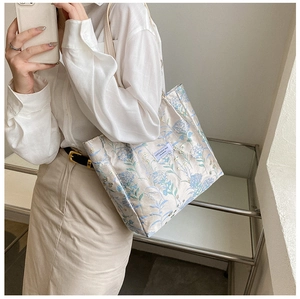 Detail of a white canvas tote bag with blue floral print and brand logo label