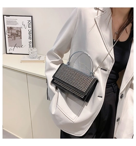 Detail of black rhinestone crossbody bag with acrylic handle worn with a white blazer