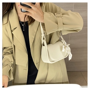 Ivory white shoulder bag with silk scarf detail worn with a beige trench coat