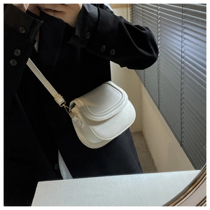 Mirror selfie showing a white leather saddle bag with gold buckle on a black blazer outfit