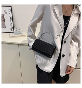 Detail of model wearing a black rhinestone crossbody bag with silver handle and chain strap