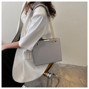 Détail du sac cabas gris à motif crocodile avec bandoulière chaîne dorée à l'épaule