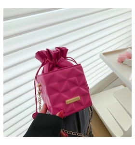 Detailed close-up of rose red cube bucket bag with quilted rhombus texture and gold chain