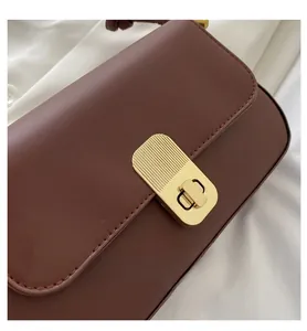 Close-up of a vintage dark brown leather handbag featuring a textured gold metal clasp