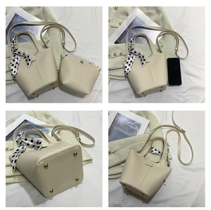 Cream bucket bag detail showing bottom metal feet, scarf handle, and inner pouch set