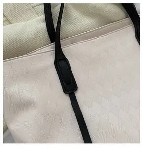 Detailed macro view of black strap stitching and beige diamond lattice texture on tote bag