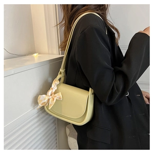 Close-up of light green crossbody bag with checkered silk scarf detail on shoulder strap
