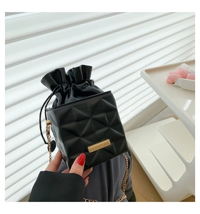 Detail of black chain bucket bag with geometric quilted pattern and heart charm