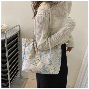 Detail of the vintage floral tote bag showing the blue botanical pattern and silver chain strap