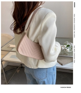 Detail view of pink crescent underarm bag with V-shaped quilting on a fashion model