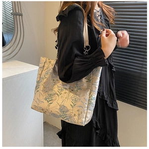 Close-up of canvas tote bag with blue floral embroidery and minimalist branded label