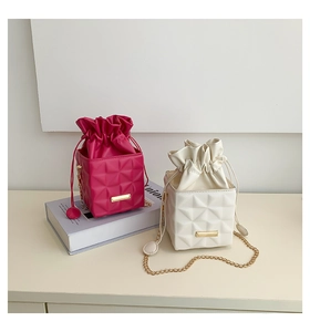 Close-up of quilted bucket bags in rose and beige with gold chain straps and drawstrings