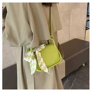 Lime green saddle crossbody bag with a decorative silk scarf on a beige coat model