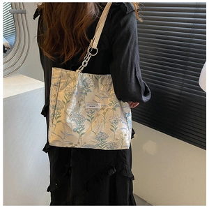 Detail of floral embroidered tote bag with silver chain strap and branding tag