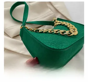 Detailed close-up of emerald green crocodile pattern leather and chunky gold chain strap