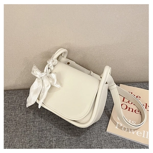 Close-up of white leather handbag featuring textured grain and silk scarf detail