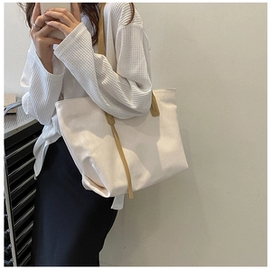 Detailed look at off-white quilted tote bag with brown leather handles on a model