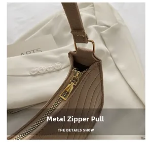 Detail of brown suede crescent bag featuring gold hardware and stitched texture