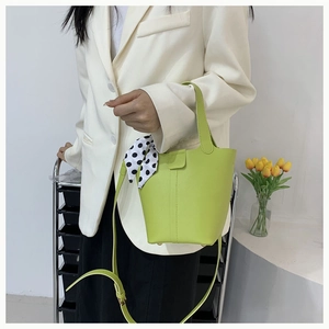 Detail view of a bright green PU leather bucket bag with a polka dot silk scarf handle