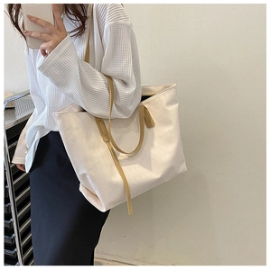 Detail view of large tote bag featuring beige diamond lattice texture and brown straps