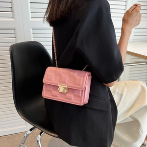 Pink quilted flap shoulder bag with gold chain strap carried by a model in casual style