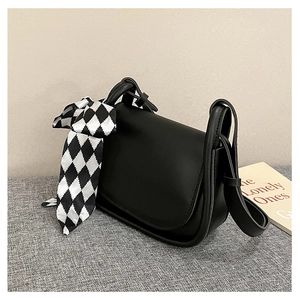Detail of black leather mini crossbody bag decorated with a checkered silk scarf strap