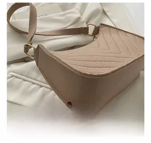 Close-up of the elegant V-shaped chevron stitching on the beige crescent shoulder bag