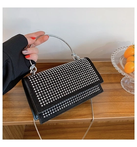 Detail of black rhinestone handbag with silver metal ring handle and chain strap