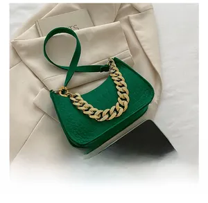 Detail view of emerald green crocodile texture handbag with chunky gold chain strap