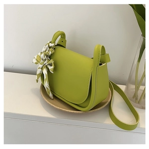 Detail of avocado green leather handbag with decorative green checkered silk scarf